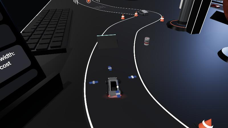 Un petit Roadster roule sur un circuit sinueux posé sur un grand bureau, entre des cônes, un clavier et une fusée